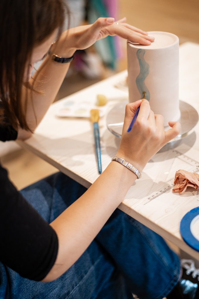 Mains d’un participant peignant une céramique lors d’un atelier créatif à Biscarrosse