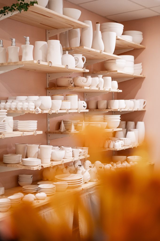 Mur rempli de céramiques disponibles à la personnalisation, prêtes à être décorées dans un café céramique à Biscarrosse